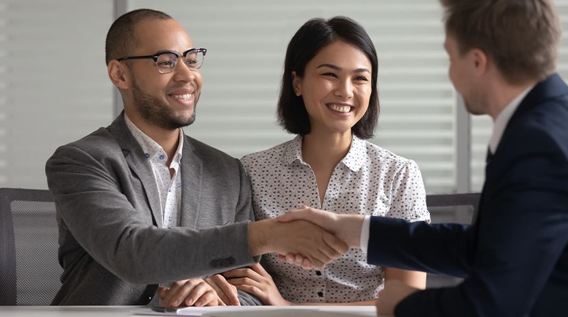 Person using calculator with small house models and laptop on table